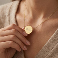 Femme touchant le collier médaillon doré gravé