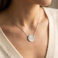 Collier médaillon argenté gravé porté sur le décolleté