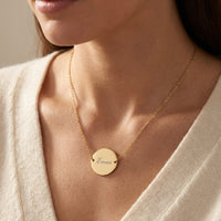 Collier médaillon doré gravé porté sur le décolleté