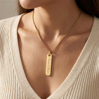 Collier barre doré gravé porté sur le décolleté