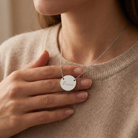 Femme touchant le collier médaillon argenté gravé